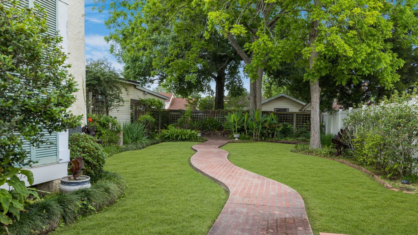 A winding brick path through the manicured garden of a historic estate, shaded by mature oaks in Abbeville, Louisiana