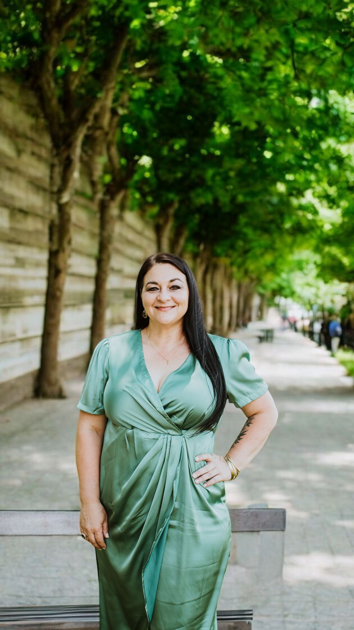 Jill Bernard, Founder and Managing Member of Vermilion Venue Co., photographed on a tree-lined promenade in a sage green dress