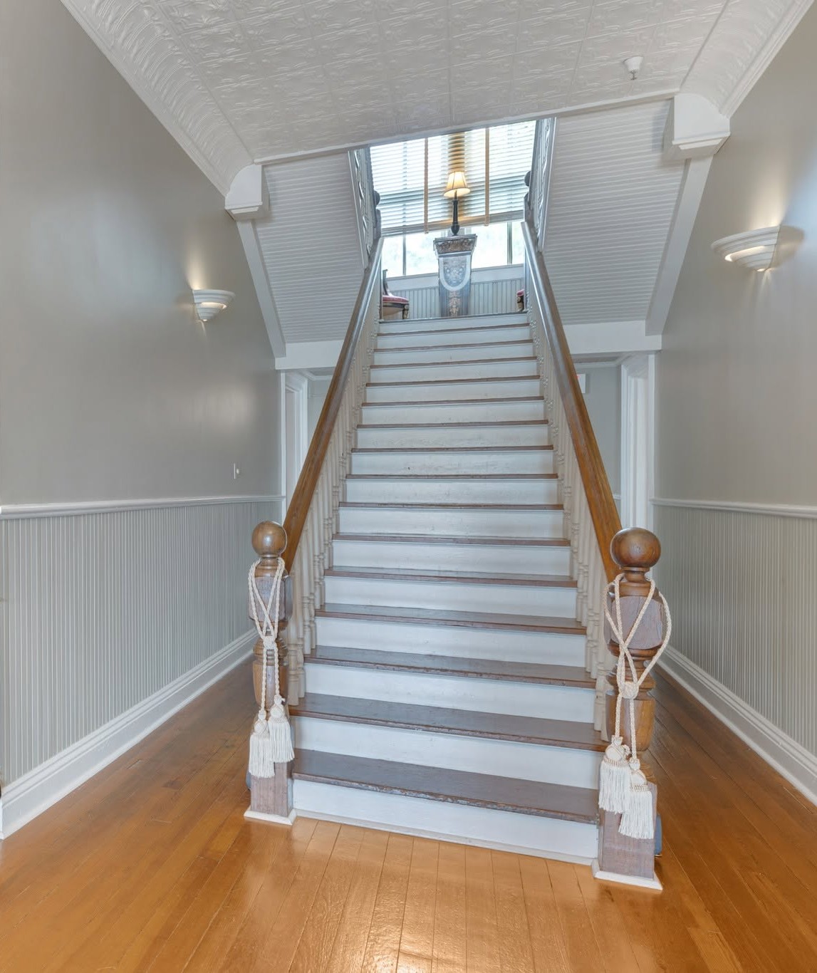 Original wooden staircase at The Caldwell House with turned newel posts, tasseled rope accents, and heart-pine floors