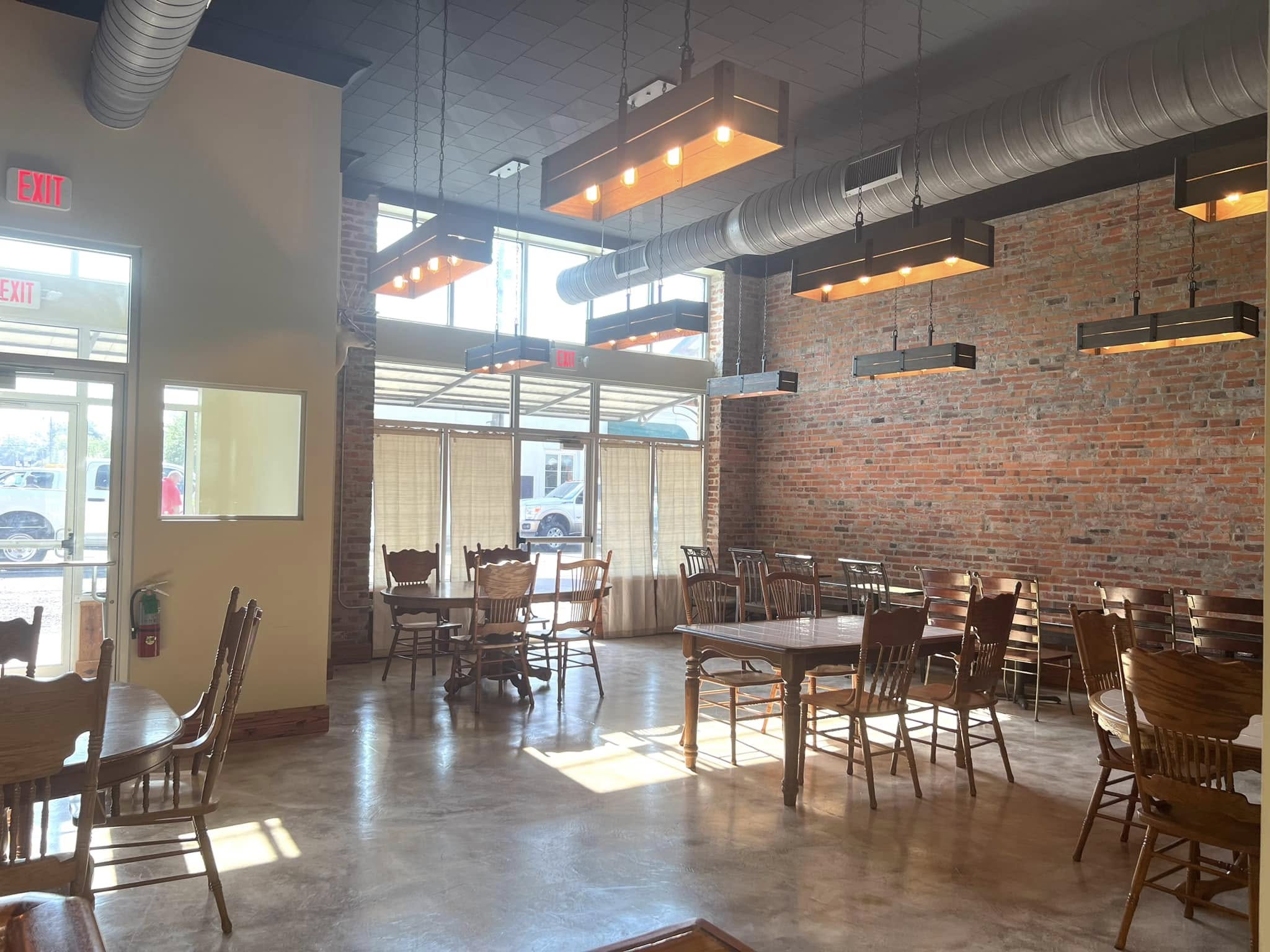 Morning sun filling The Russo's 1914 interior through tall storefront windows, with exposed brick, antique wood tables, and crate-style pendant lights