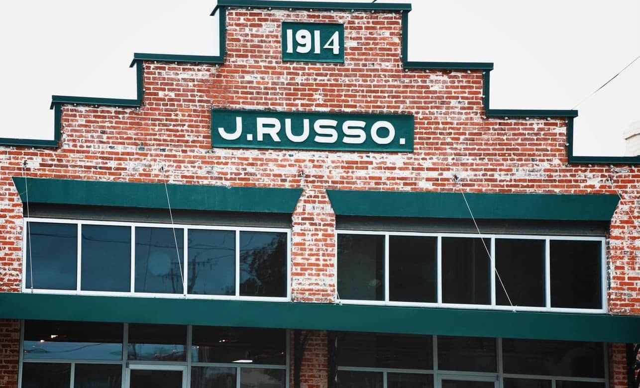 The stepped brick facade of the 1914 J. Russo building in downtown Abbeville, with its original painted J. Russo and 1914 signs and deep green awnings
